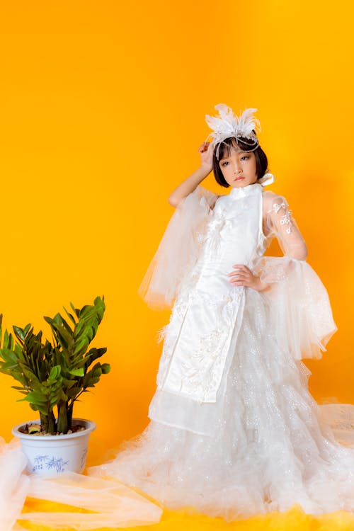 Girl in White Dress Holding Green Plant