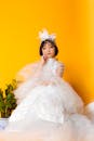 一位身着白色婚纱的年轻女孩，优雅地坐在充满活力的黄色背景前