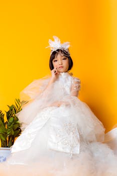 一位身着白色婚纱的年轻女孩，优雅地坐在充满活力的黄色背景前