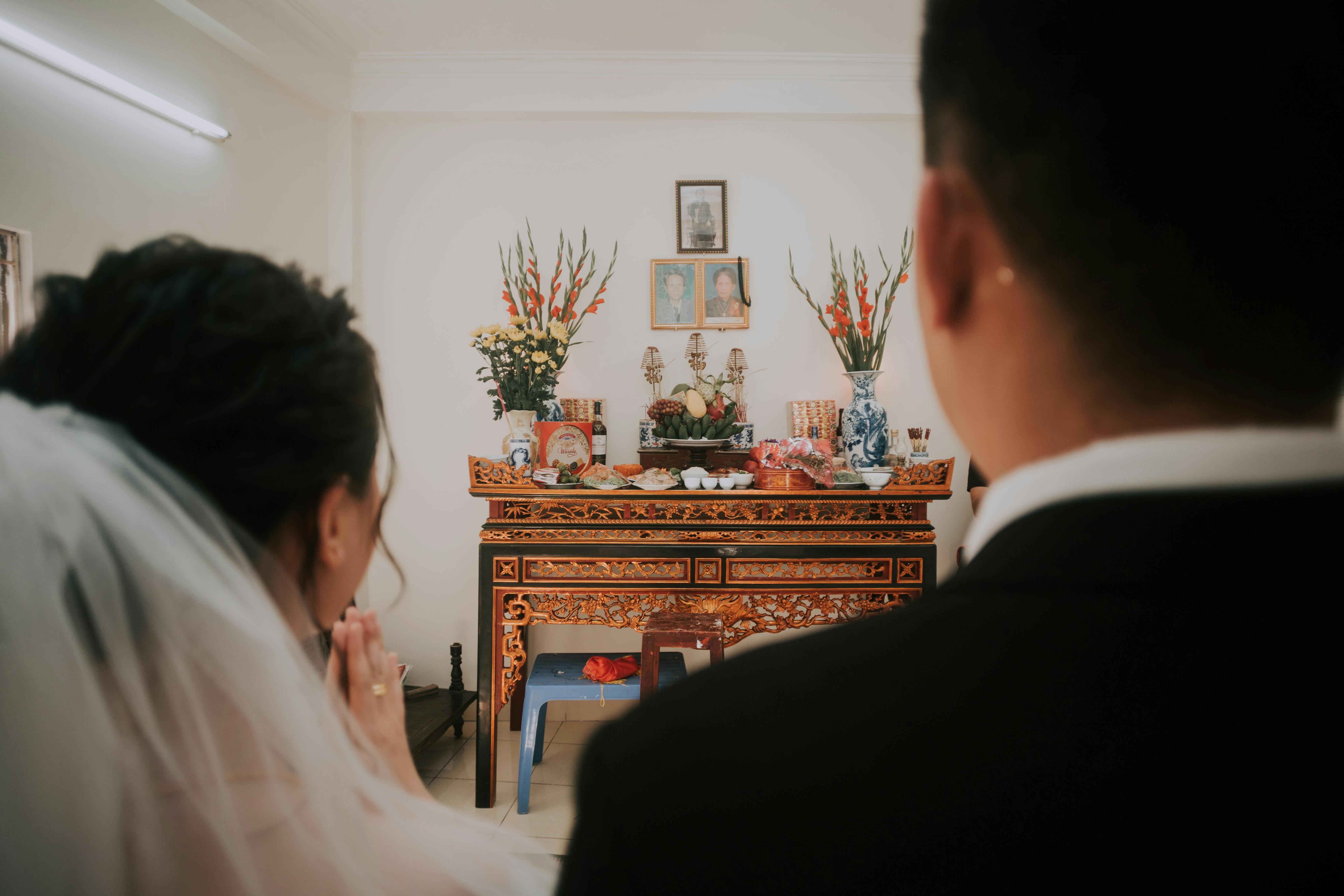 Back view of blurred groom and bride against ornamental shrine during ceremony of marriage
