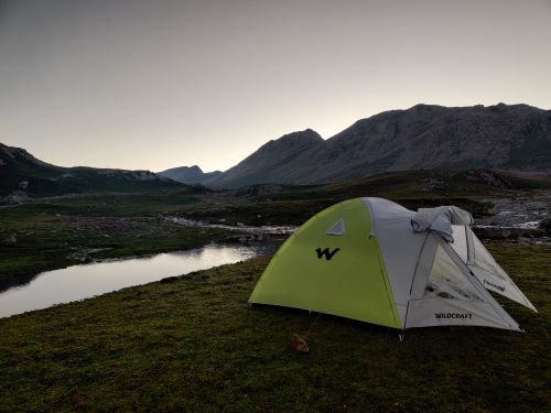 Free A tranquil campsite with a tent by a mountain lake at dusk, perfect for outdoor adventures. Stock Photo