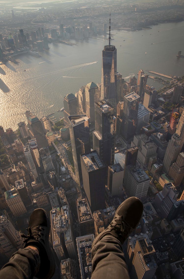 Man Dangling Legs Above Modern City Downtown