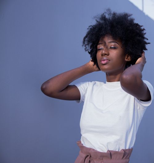 Free Charming portrait of African American woman with natural afro hairstyle, eyes gently closed, wearing a white shirt. Stock Photo