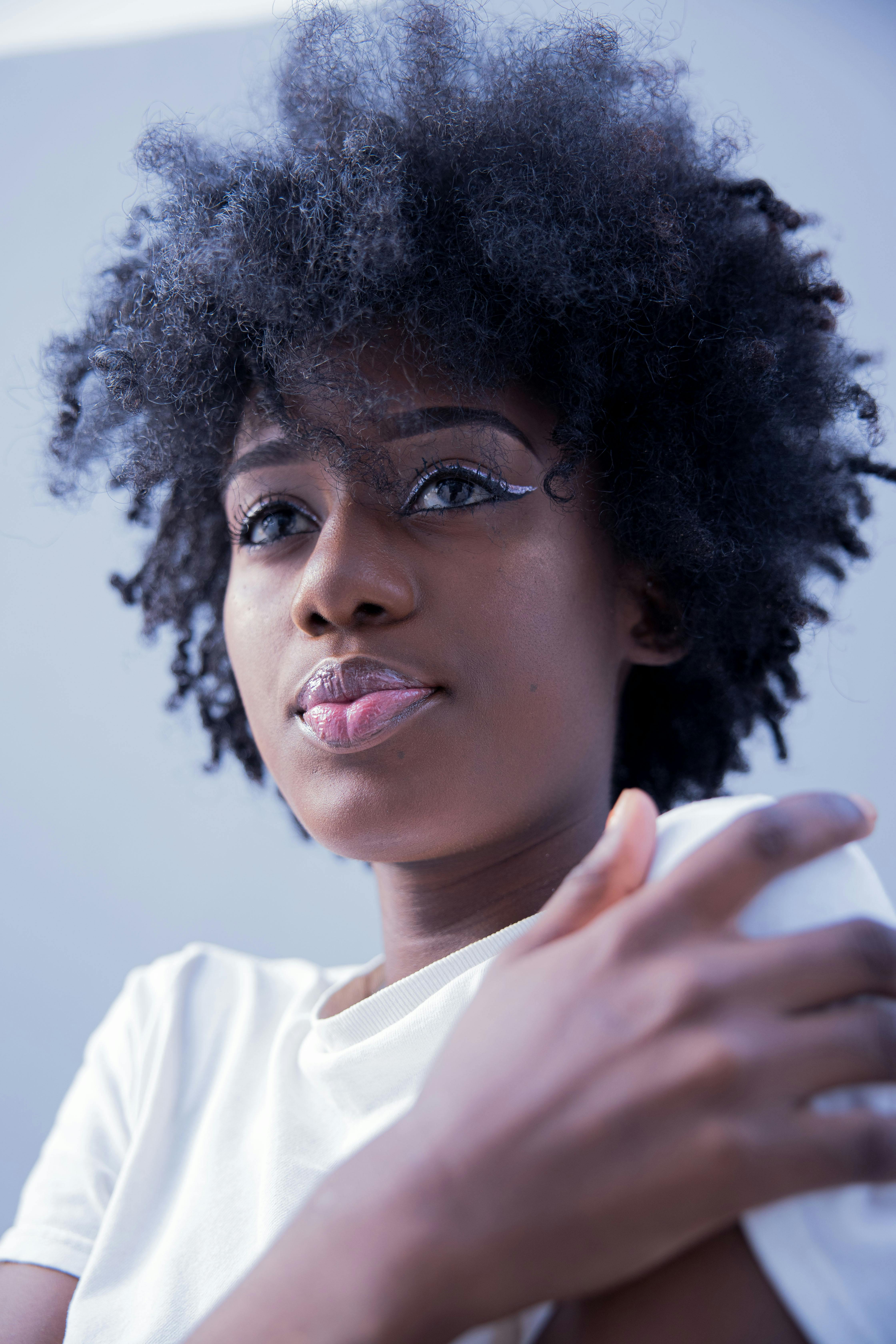 Vibrant portrait of a black woman with curly natural hair, wearing a white shirt.