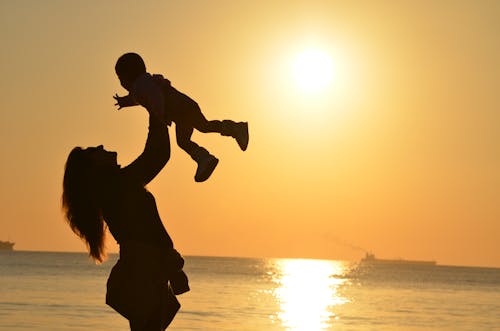 女人攜帶嬰兒在海灘在日落