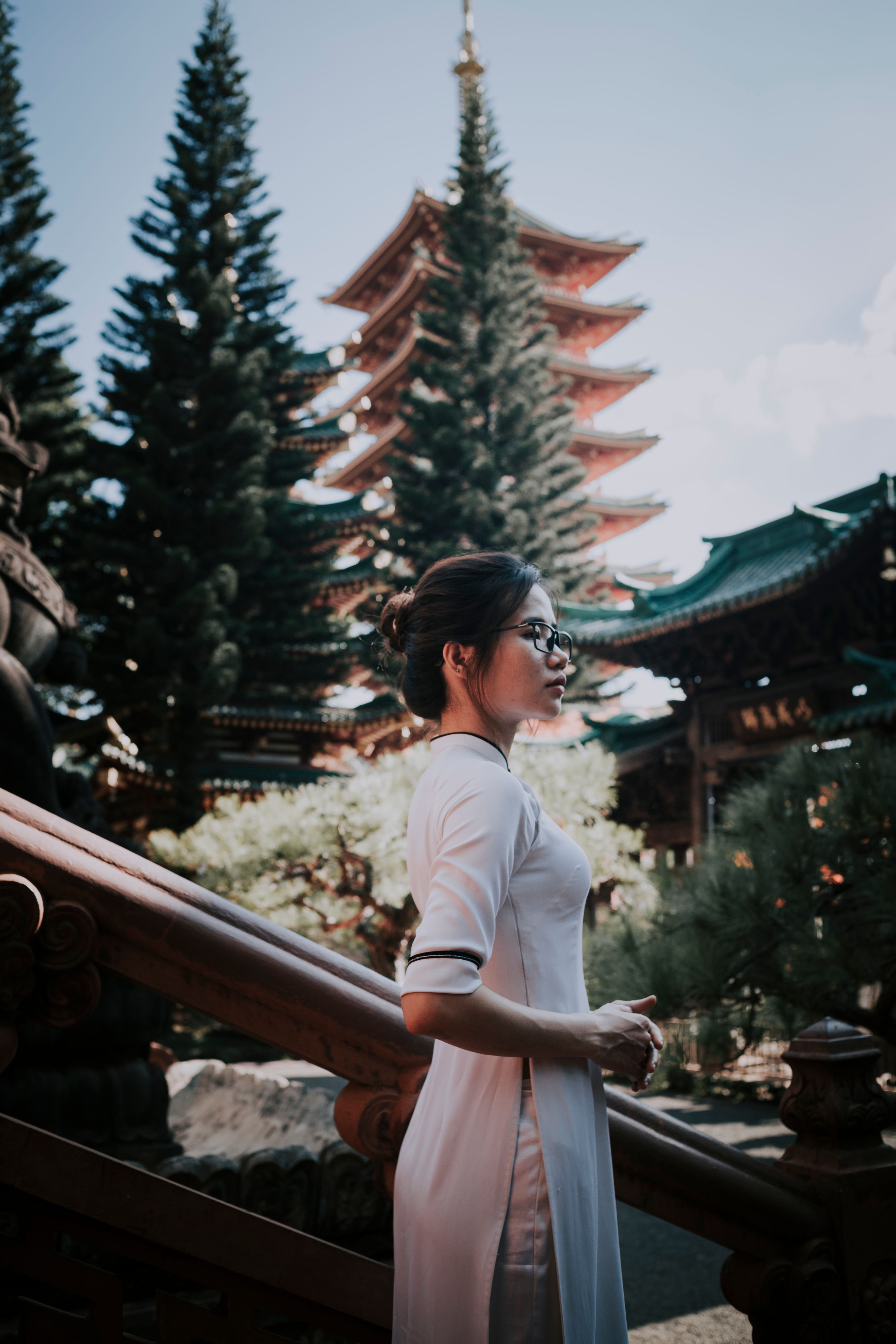 一位身着传统服装的亚洲妇女，侧身静立在宁静花园的佛塔旁
