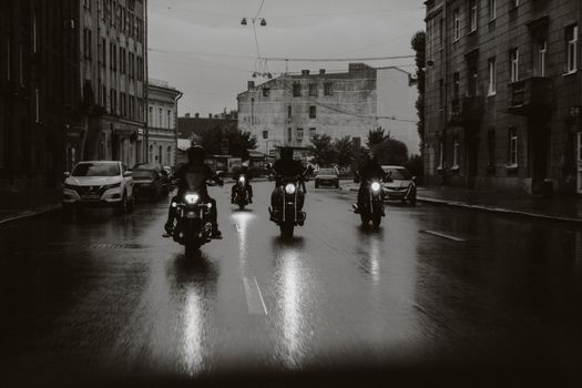 夜晚，一群骑自行车的人穿过城市雨中的街道
