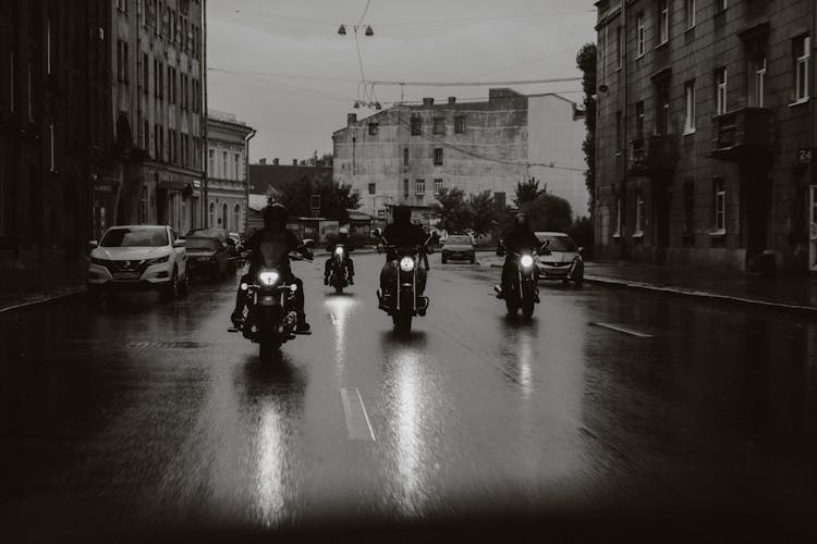 People Riding Motorcycles On The Wet Road