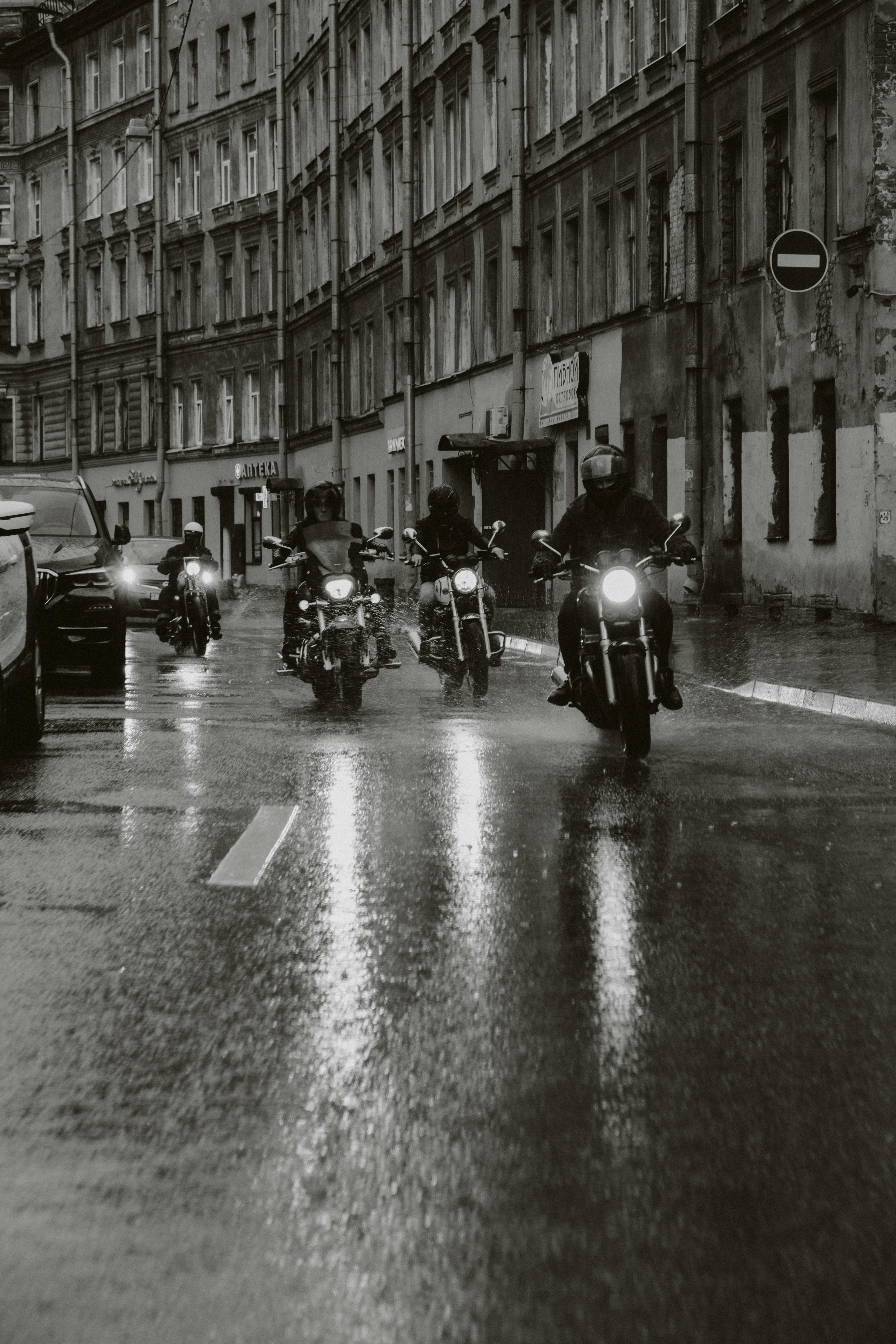 Group of motorcyclists traversing an urban street in the rain, showcasing freedom and adventure.