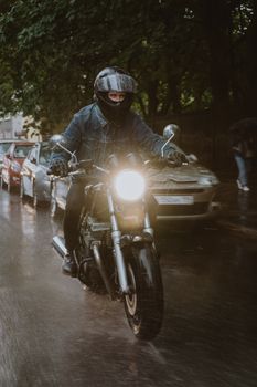 雨天，一名戴着头盔的摩托车手在湿滑的道路上骑行