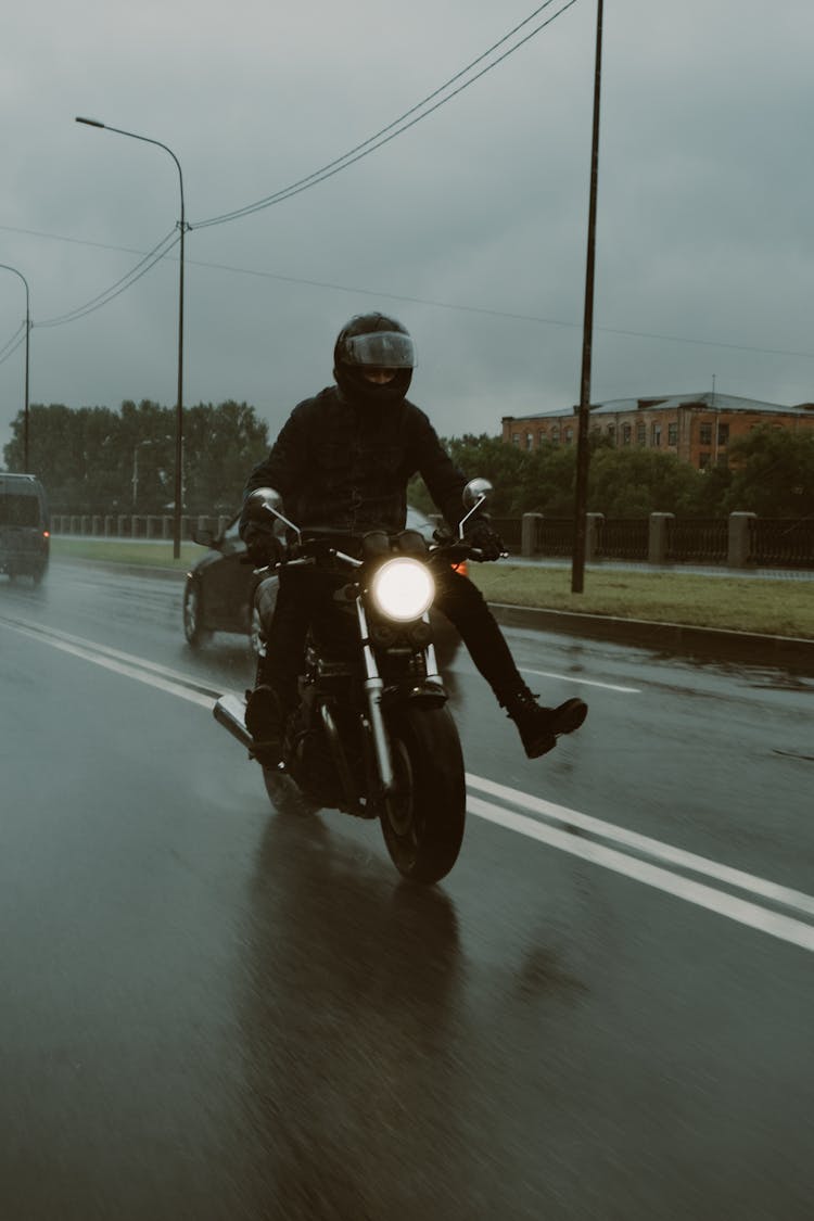 A Man In Black Helmet Riding Motorcycle On Road