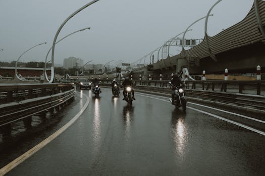 Motorcyclists navigate a wet highway under a gloomy sky, showcasing urban transportation.