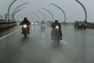 摩托车手在雨中驶过潮湿的高速公路桥，车头灯穿透了黑暗
