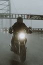 摩托车手冒雨在高速公路上骑行，凸显了交通挑战