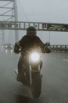 摩托车手冒雨在高速公路上骑行，凸显了交通挑战