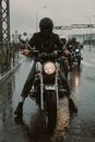 在反光的城市高速公路上，戴着头盔的骑行者冒雨前行，展现了友情与冒险精神