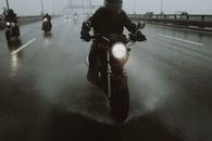 一群摩托车手在高速公路上冒雨骑行，溅起动感的水花