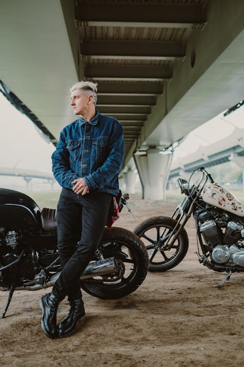 Man Wearing a Denim Jacket Posing with the Motorcycles