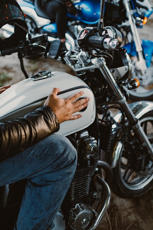 Person in Blue Denim Jeans Sitting on White Motorcycle