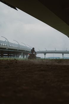 动态镜头中，一名摩托车手在雾霭笼罩的未来派桥梁下骑行