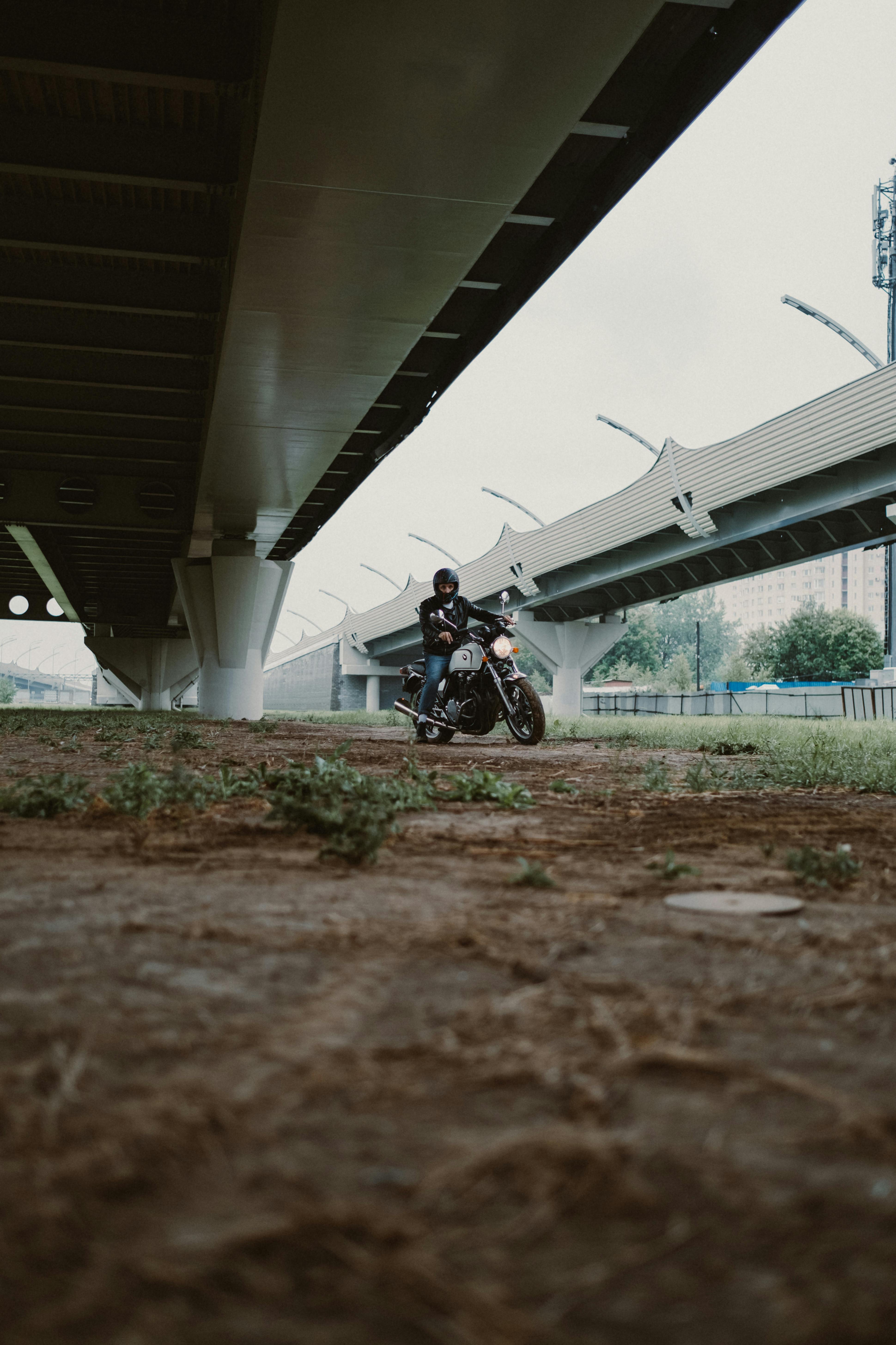 一名穿着安全装备的摩托车手正在城市的一座现代化桥梁下行驶