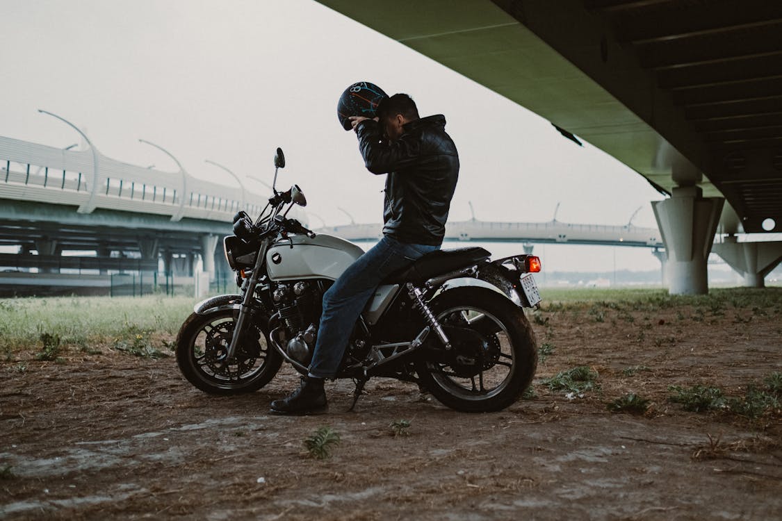 Man in Black Jacket Sitting On A Motorcycle Putting On His Helmet