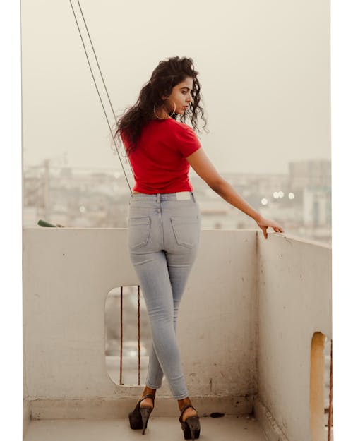 A Woman in Red Shirt Standing on a Rooftop while Looking Afar