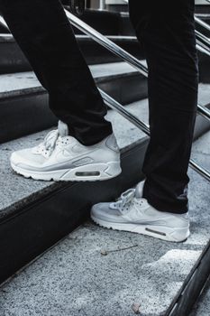 Stylish white sneakers walking on modern urban staircase outdoors.