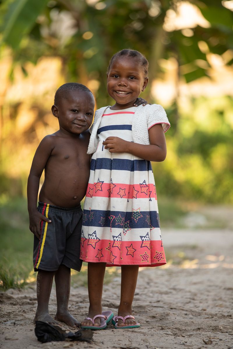 Boy and girl hugging and smiling together on sandy ground in the countryside