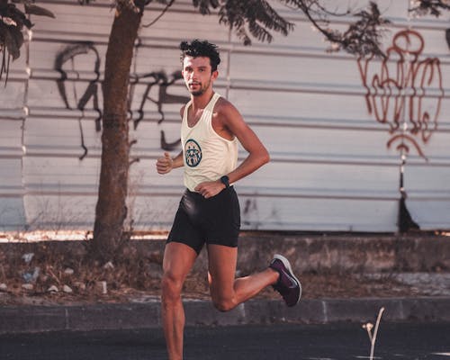 Strong sportsman running fast along street