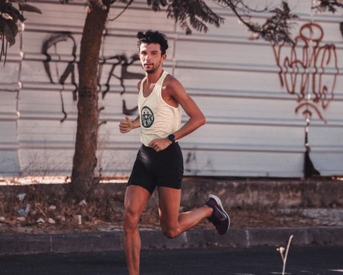 Free Muscular athletic man in sportswear running along paved street during training in sunny day Stock Photo