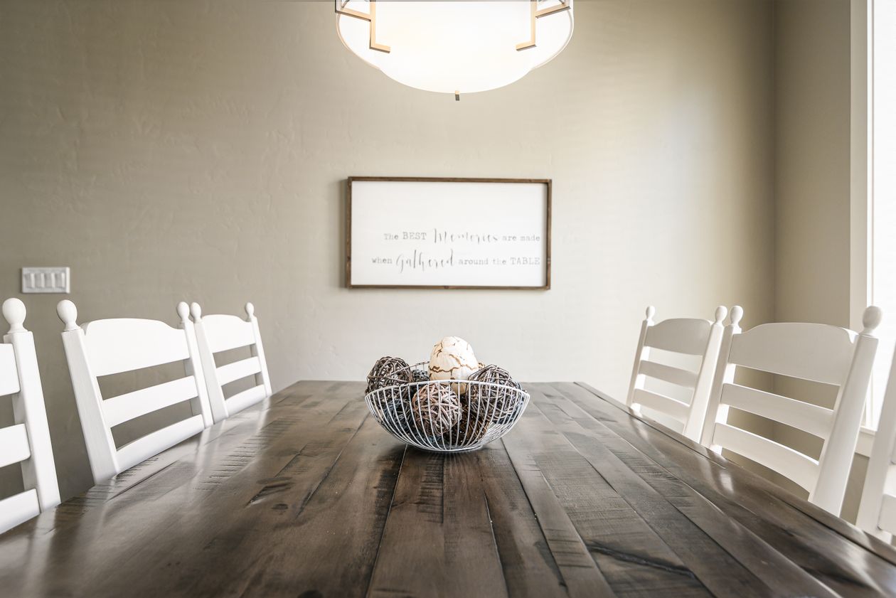 Dark wood dining table with six white ladder-back chairs