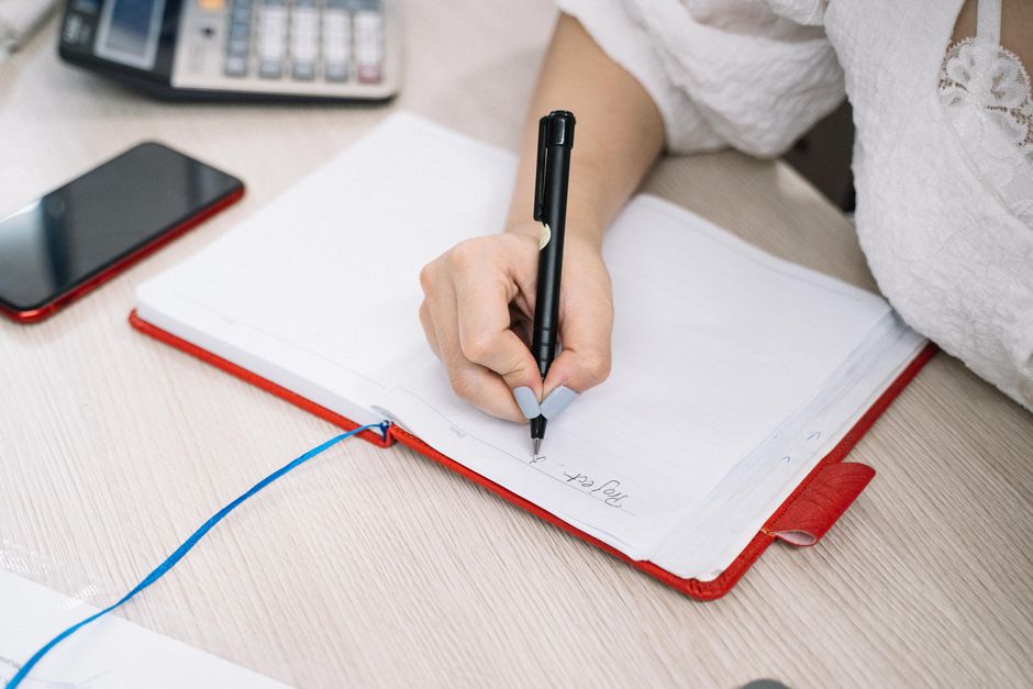 measure ai search visibility, person taking notes at desk with notebook and coffee tracking brand mentions