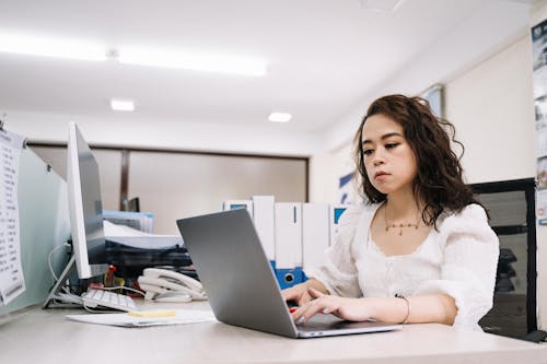 Woman in White Lace Top Using Laptop