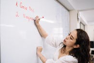 Woman Holding a Pen Writing on Whiteboard