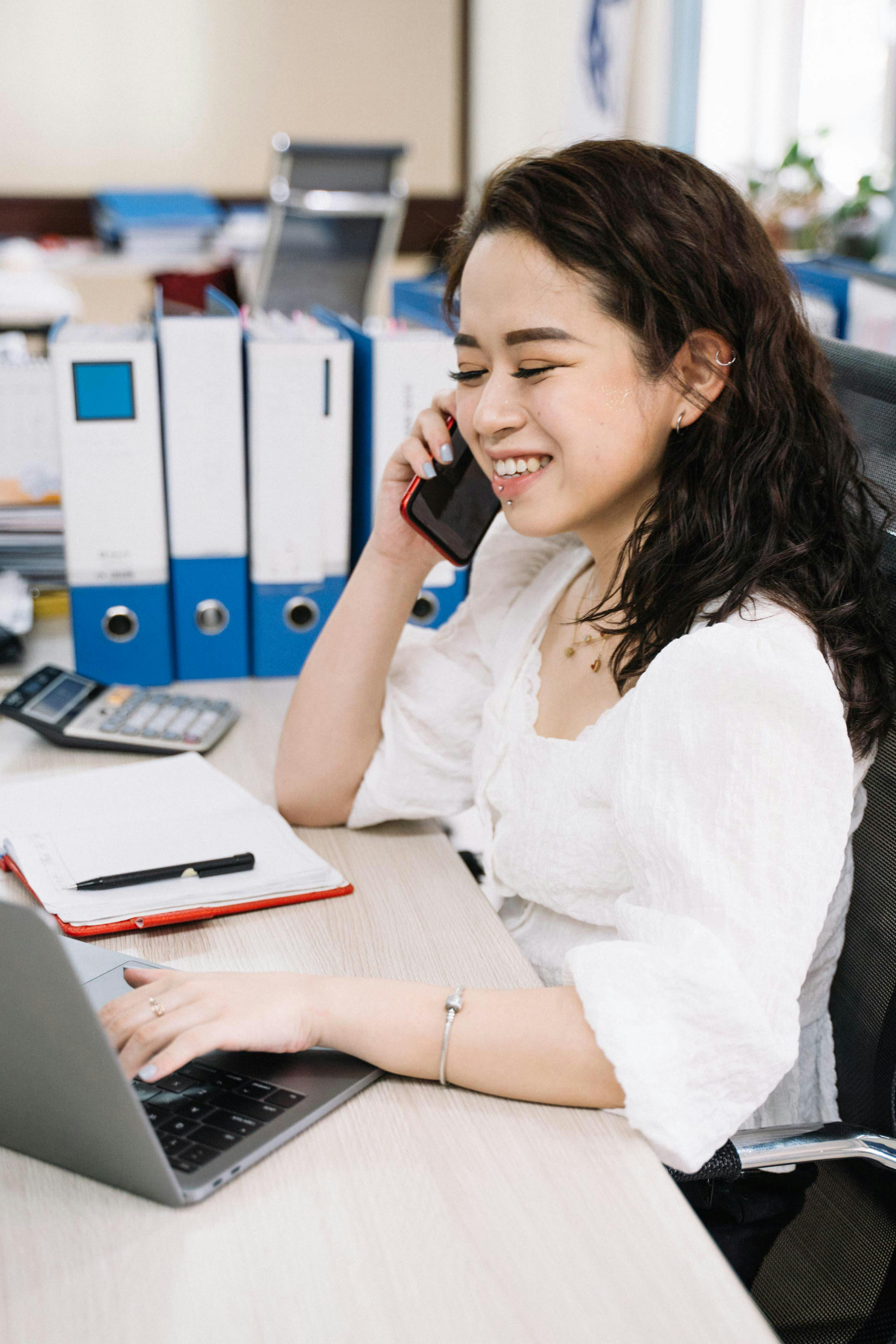 woman having a phone call while using laptop