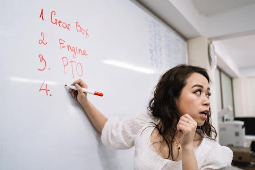 Woman writing mechanical terms on a whiteboard in an educational setting.
