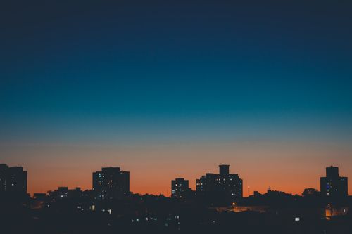 Free Picturesque scenery of contemporary buildings silhouettes in city against bright cloudless sunset sky Stock Photo