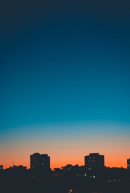 Colorful cloudless sunset sky over illuminated buildings in residential district of modern city