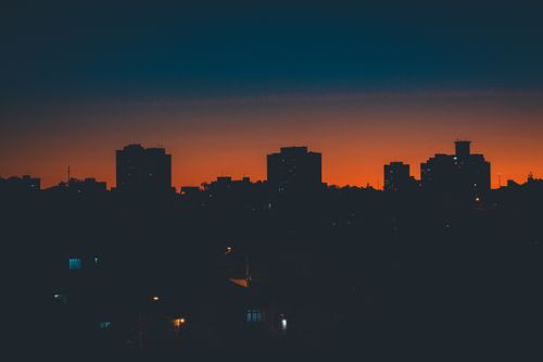 Free Picturesque skyline of modern dark city with silhouettes of residential buildings against cloudless sunset sky Stock Photo