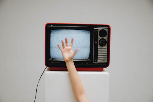 A classic retro television displaying static with a hand reaching towards the screen.