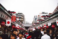 日本街头市场热闹非凡，挂满了旗帜和灯笼，聚集着多元化的人群