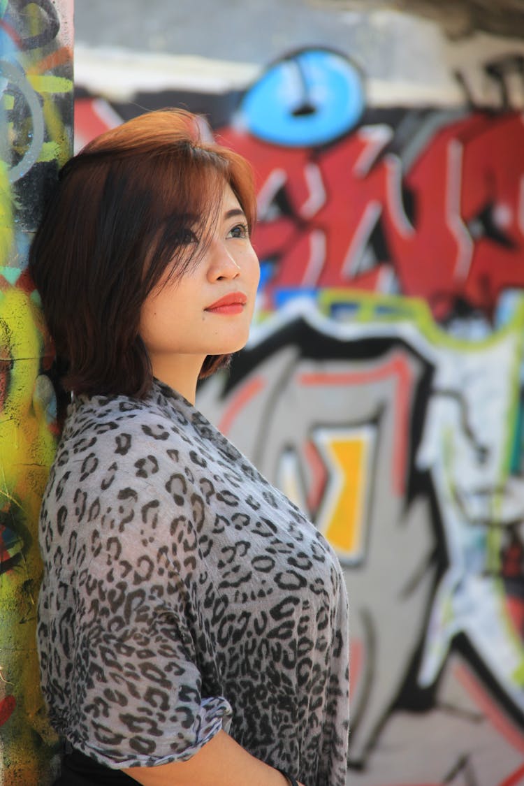 Woman With Leopard Print Scarf Leaning Against A Graffiti Wall