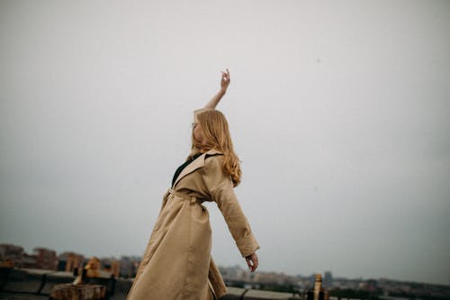 Woman in Brown Coat With Her Right Arm Raised