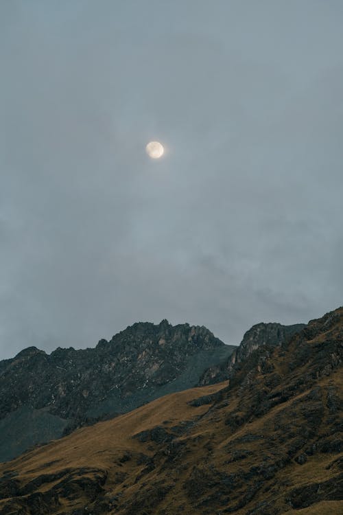 Mountain Peaks Under a Moon During Dawn