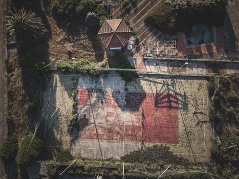 Aerial view of destructed sports ground located near tropical trees and gazebo in countryside on sunny day