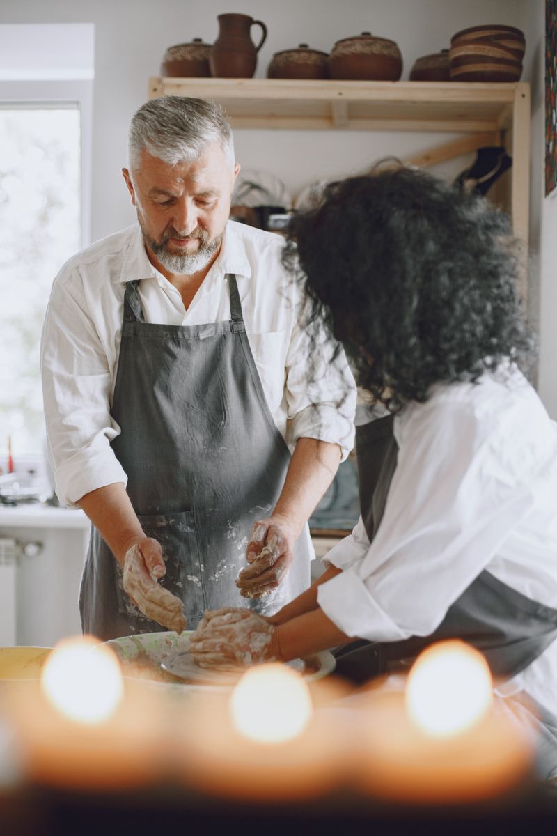 A teacher guiding a student's hands on the pottery wheel
