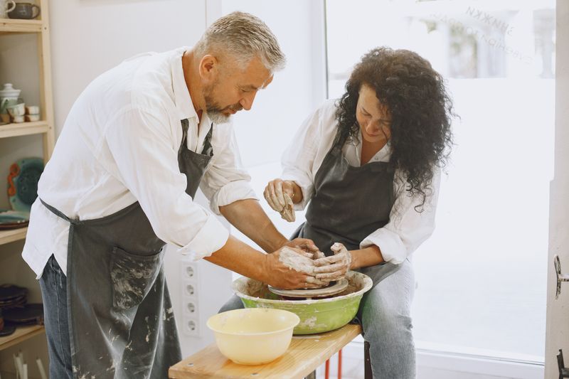 Two students shaping clay together at a studio table