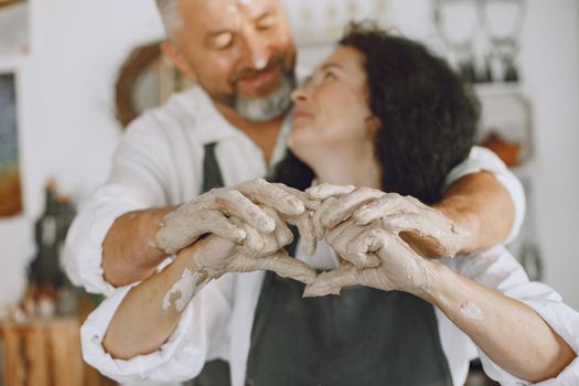 Couple sharing a loving embrace while creating pottery together, symbolizing love and artistry.