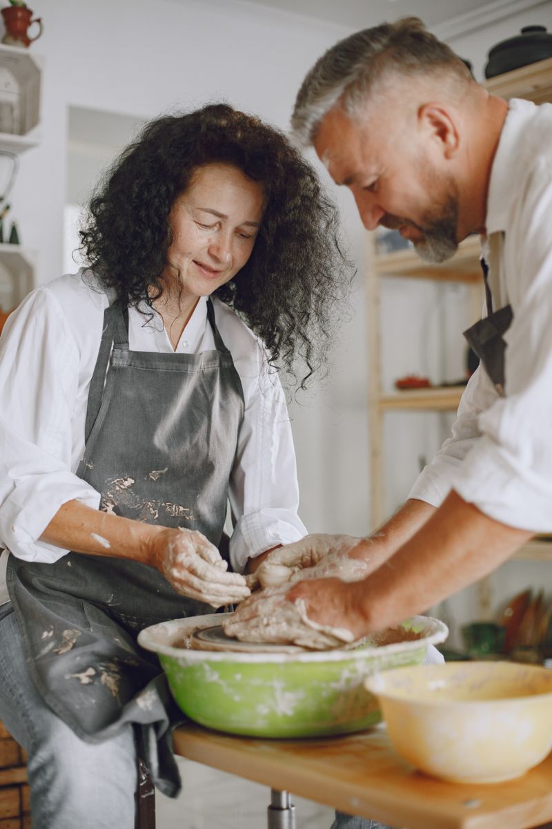 Two makers shaping clay together at the wheel